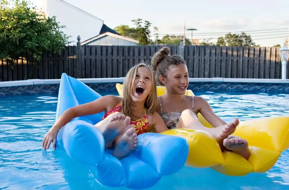two girls sitting on floaties in pool